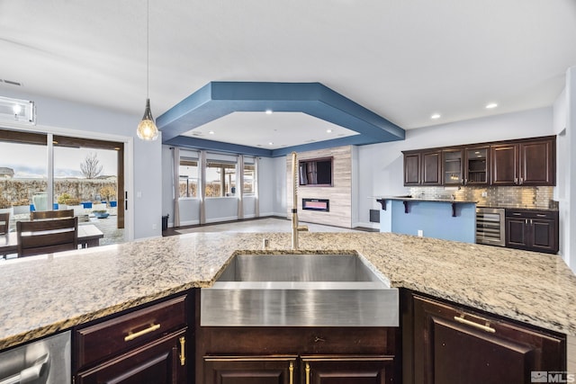 kitchen with sink, hanging light fixtures, beverage cooler, tasteful backsplash, and dark brown cabinets