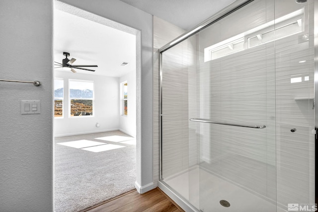 bathroom with a shower with door, wood-type flooring, and ceiling fan