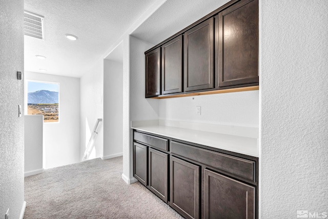 hallway with light carpet and a textured ceiling