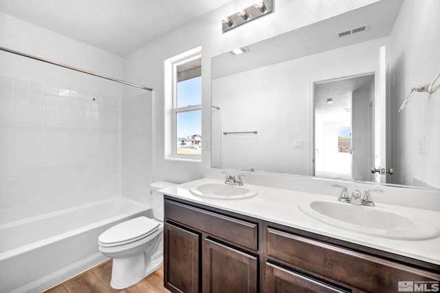 full bathroom featuring shower / tub combination, hardwood / wood-style floors, vanity, a wealth of natural light, and toilet