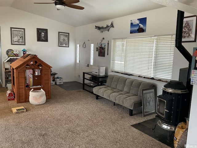 living room featuring carpet, ceiling fan, a wood stove, and vaulted ceiling