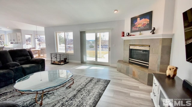 living room with a tile fireplace and light hardwood / wood-style flooring