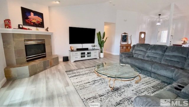 living room with a fireplace, light hardwood / wood-style floors, and vaulted ceiling