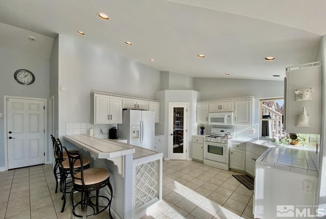 kitchen featuring white appliances, backsplash, tile counters, light tile patterned flooring, and kitchen peninsula