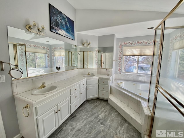 bathroom featuring vanity, a relaxing tiled tub, and lofted ceiling