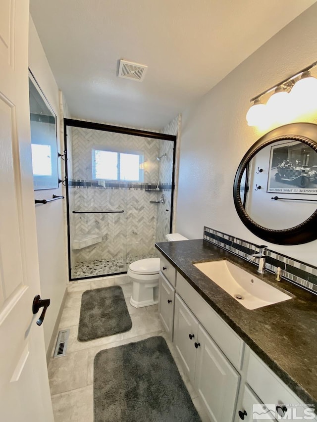 bathroom with toilet, vanity, tile patterned floors, and a shower with door