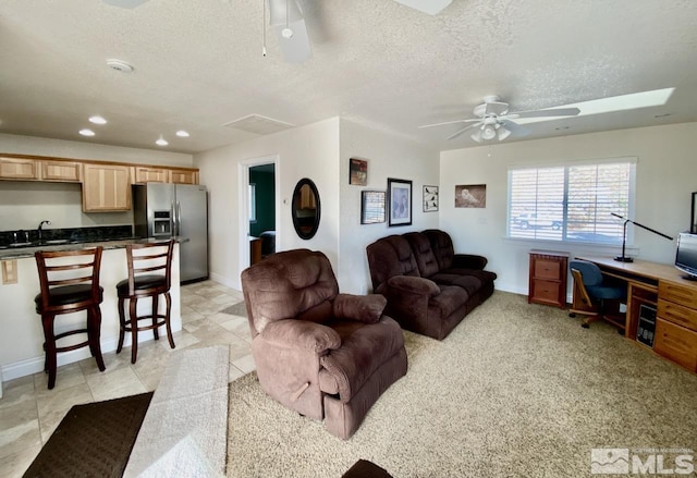 living room featuring ceiling fan, sink, and a textured ceiling