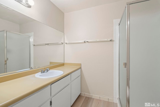 bathroom with a shower with shower door, wood-type flooring, and vanity