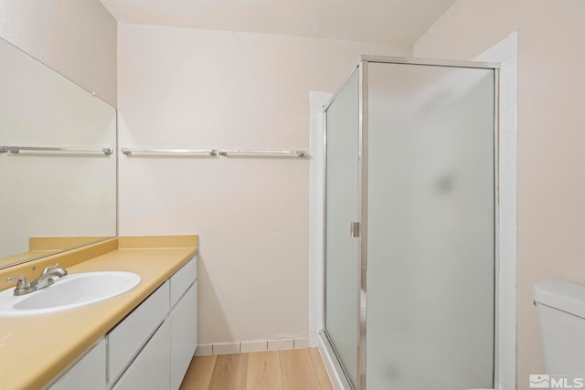 bathroom featuring hardwood / wood-style flooring, vanity, toilet, and a shower with door