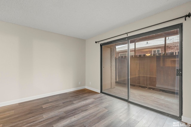 unfurnished room with hardwood / wood-style flooring and a textured ceiling