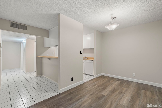 spare room featuring a textured ceiling and light hardwood / wood-style flooring