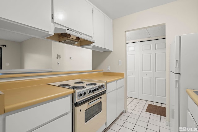 kitchen with white cabinets, light tile patterned floors, and white appliances