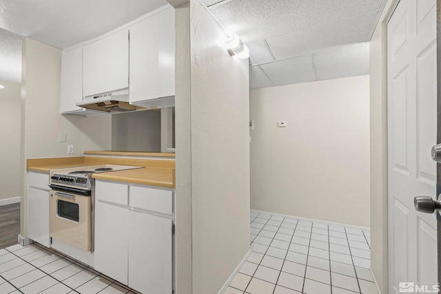 kitchen with electric range, light tile patterned flooring, white cabinetry, and range hood