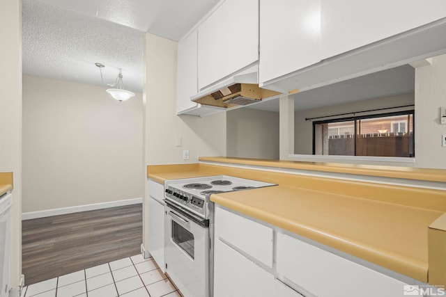 kitchen with electric range oven, a textured ceiling, extractor fan, white cabinetry, and light tile patterned flooring