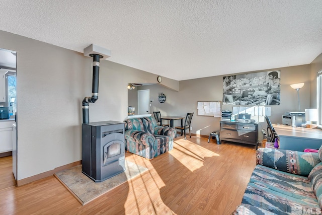 living room featuring a textured ceiling, light hardwood / wood-style flooring, and a wood stove