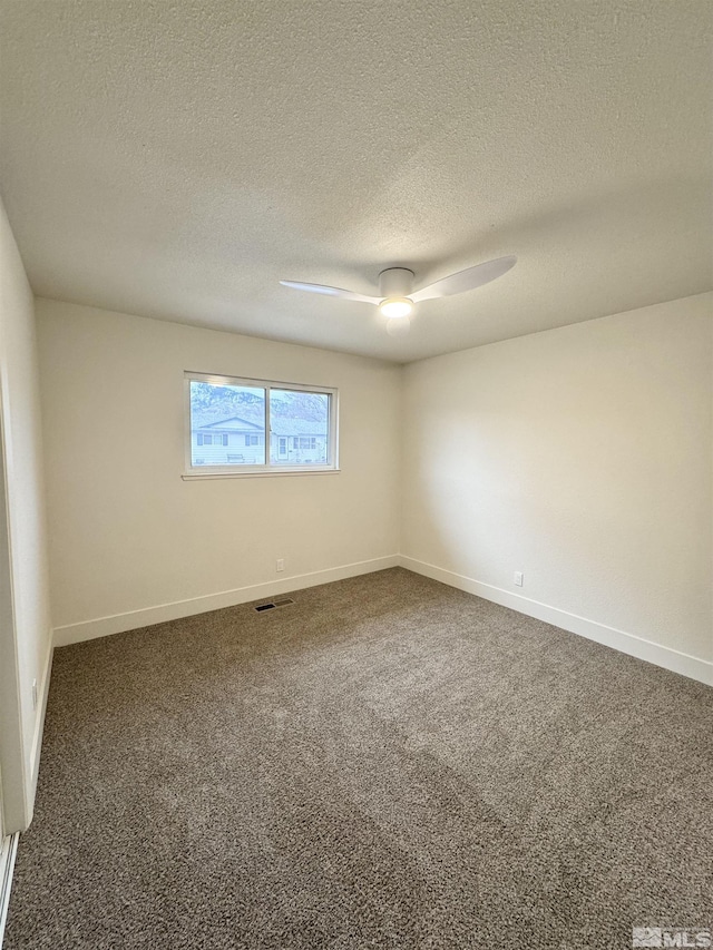 empty room with a textured ceiling and dark carpet