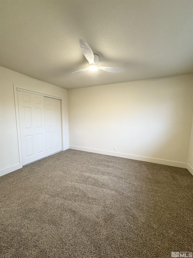 unfurnished bedroom with carpet flooring, ceiling fan, a textured ceiling, and a closet