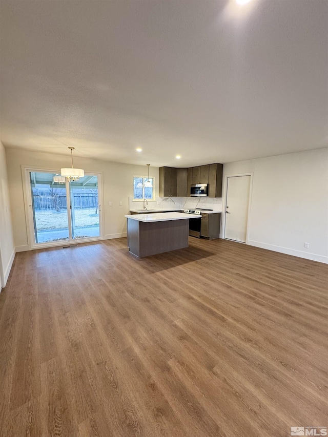 kitchen with dark brown cabinetry, sink, stainless steel appliances, pendant lighting, and a kitchen island