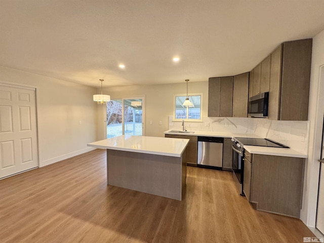 kitchen with decorative light fixtures, a kitchen island, appliances with stainless steel finishes, and tasteful backsplash