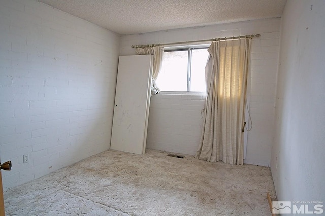 empty room featuring a textured ceiling and brick wall