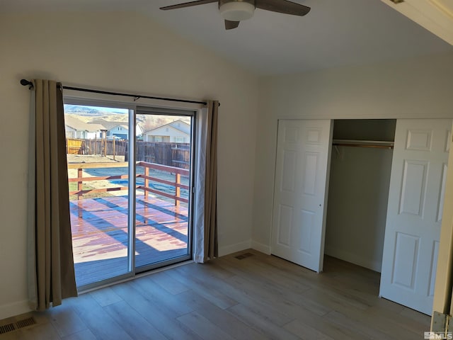 unfurnished bedroom featuring access to exterior, vaulted ceiling, ceiling fan, light hardwood / wood-style floors, and a closet