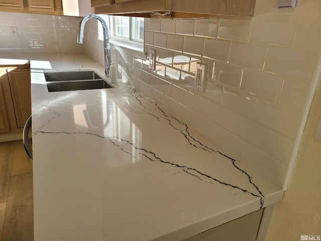 details featuring sink, light stone countertops, and backsplash