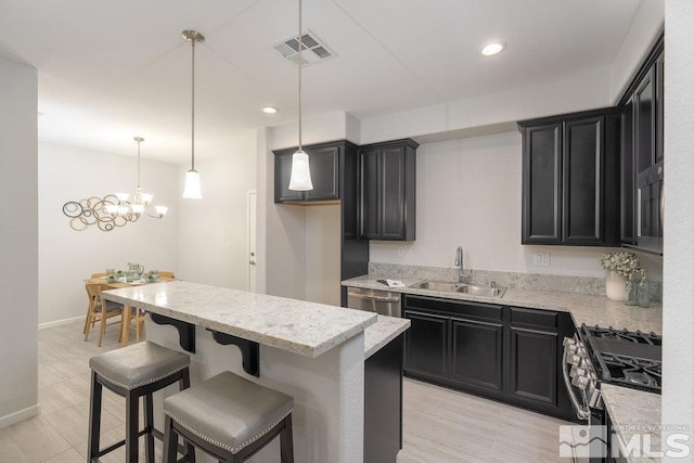 kitchen with sink, an inviting chandelier, pendant lighting, a breakfast bar, and appliances with stainless steel finishes