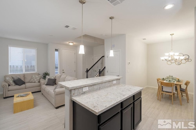 kitchen featuring light stone countertops, an inviting chandelier, decorative light fixtures, and a kitchen island