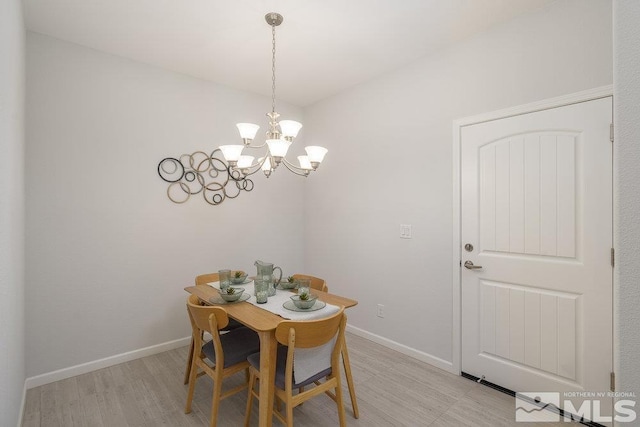 dining space featuring light wood-type flooring and an inviting chandelier