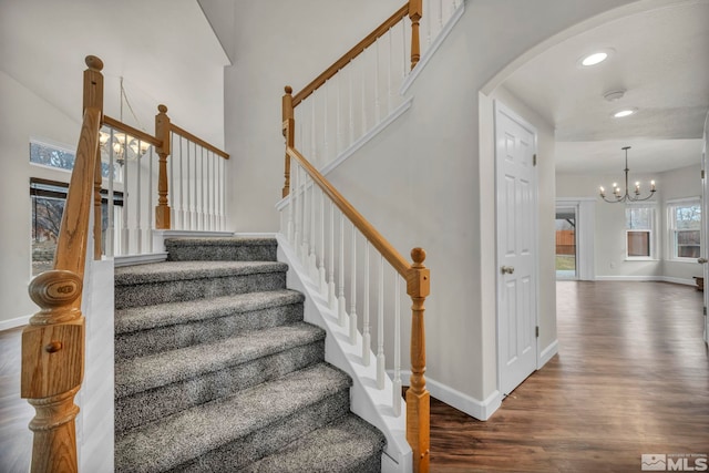 stairway with hardwood / wood-style flooring and a notable chandelier