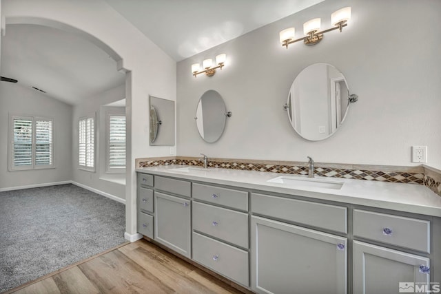 bathroom with hardwood / wood-style flooring, vanity, and vaulted ceiling