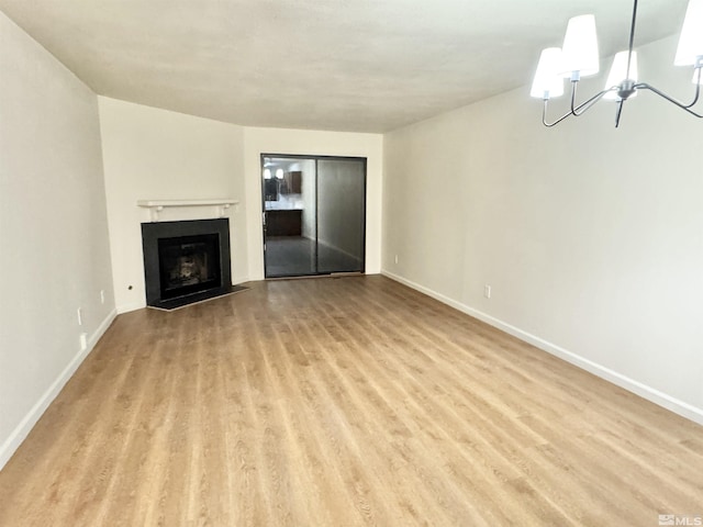 unfurnished living room with an inviting chandelier and light hardwood / wood-style floors