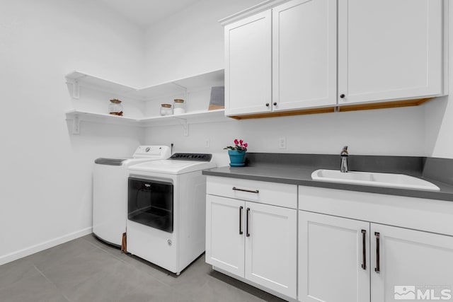 laundry area featuring separate washer and dryer, sink, light tile patterned flooring, and cabinets