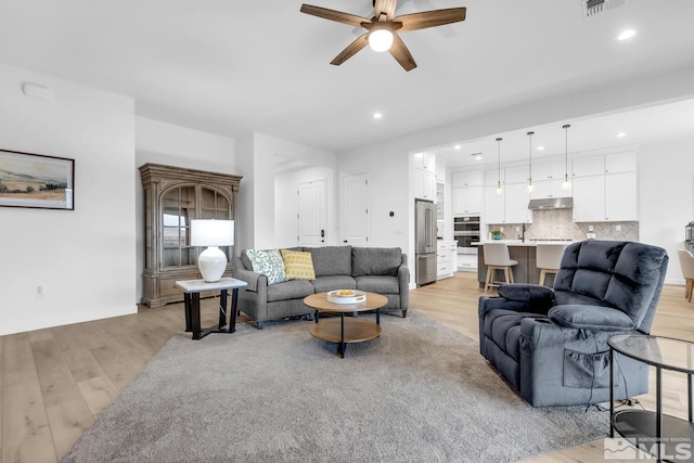 living room with ceiling fan and light wood-type flooring