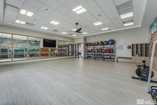 gym featuring ceiling fan, a drop ceiling, and light hardwood / wood-style flooring