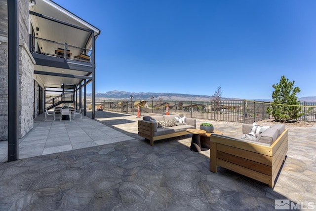 view of patio featuring a mountain view, a balcony, and an outdoor living space