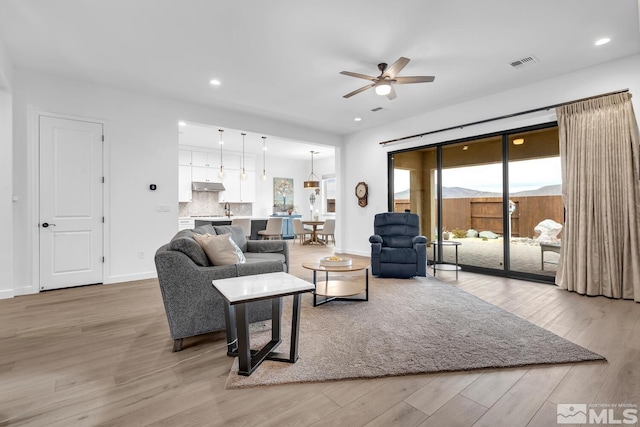 living room featuring ceiling fan and light hardwood / wood-style floors