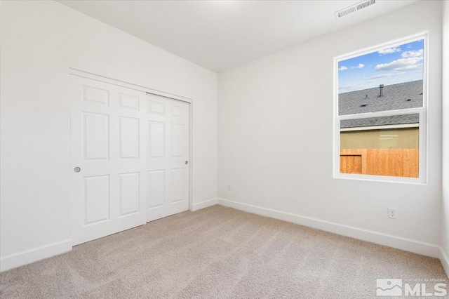 unfurnished bedroom with light colored carpet and a closet