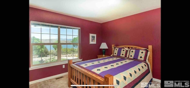 carpeted bedroom featuring multiple windows and a water view