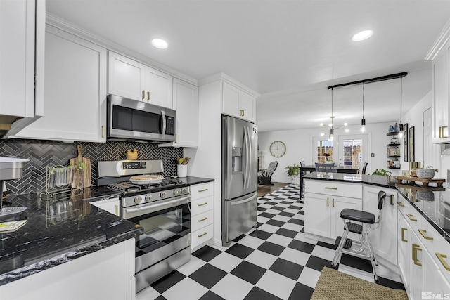 kitchen with white cabinets, decorative light fixtures, backsplash, and appliances with stainless steel finishes