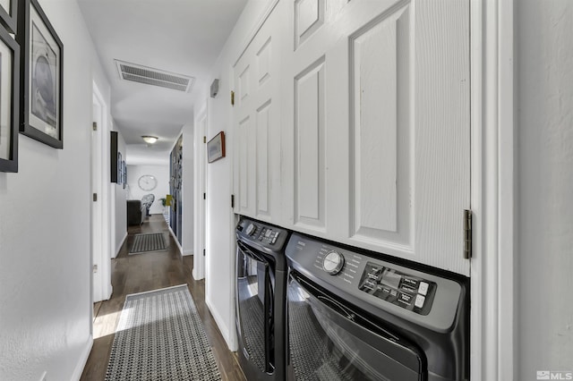 laundry room with washer and dryer, cabinets, and dark hardwood / wood-style floors