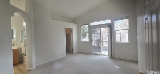 carpeted empty room featuring a wealth of natural light and high vaulted ceiling