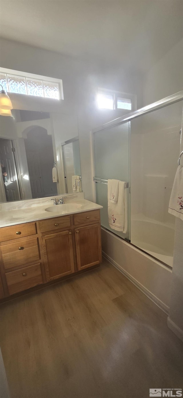 bathroom with hardwood / wood-style floors, vanity, and bath / shower combo with glass door