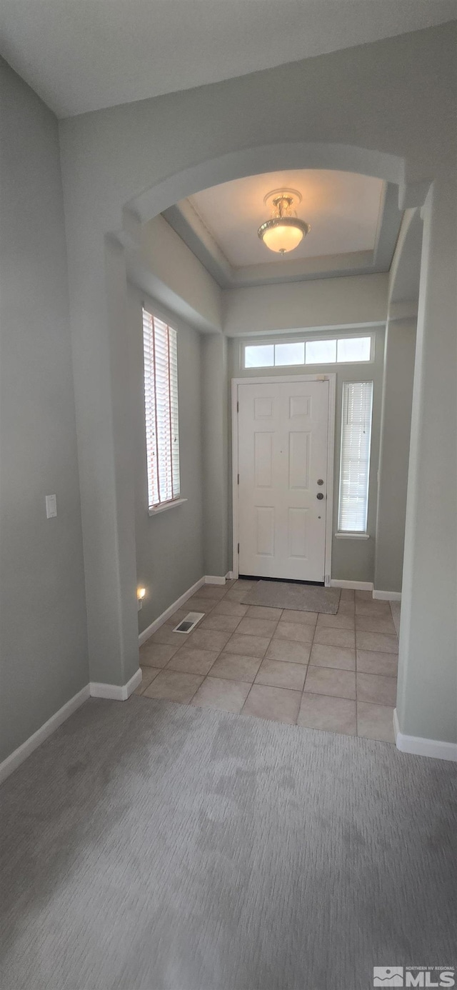 entrance foyer with a raised ceiling and light tile patterned floors