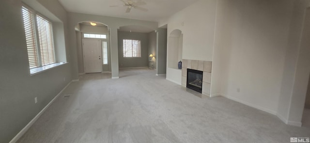 unfurnished living room featuring ceiling fan, a fireplace, and light colored carpet