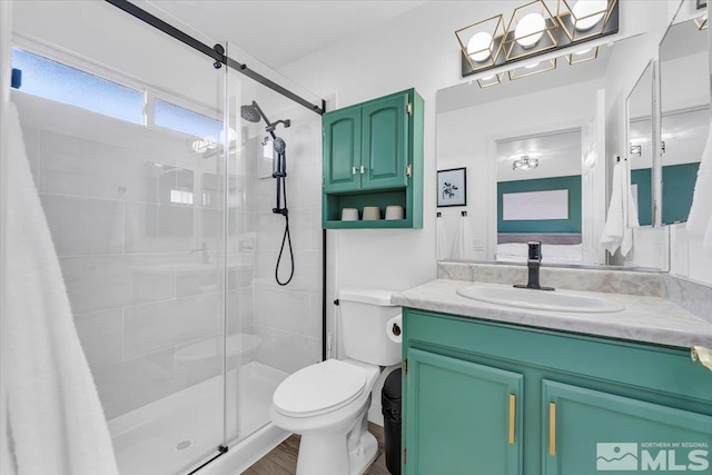 bathroom featuring a shower with door, vanity, hardwood / wood-style floors, and toilet