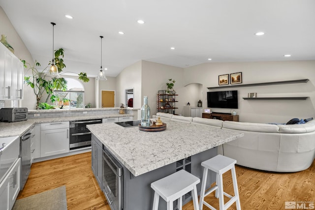 kitchen featuring a breakfast bar, a kitchen island, white cabinetry, and lofted ceiling