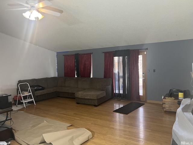 living room with a textured ceiling, light hardwood / wood-style floors, and ceiling fan