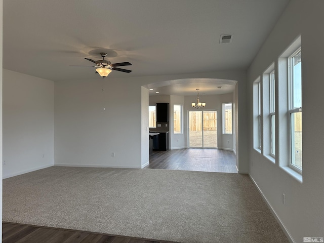 carpeted spare room with ceiling fan with notable chandelier and a wealth of natural light