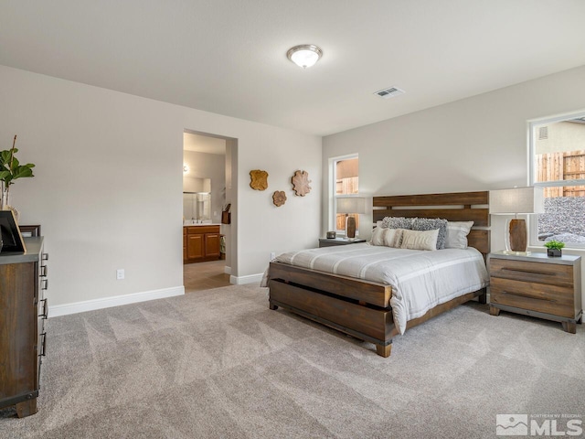 bedroom with connected bathroom and light colored carpet